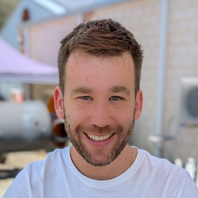 Michael Leaney, founder of lowerSpendings, smiling outdoors in a white T-shirt